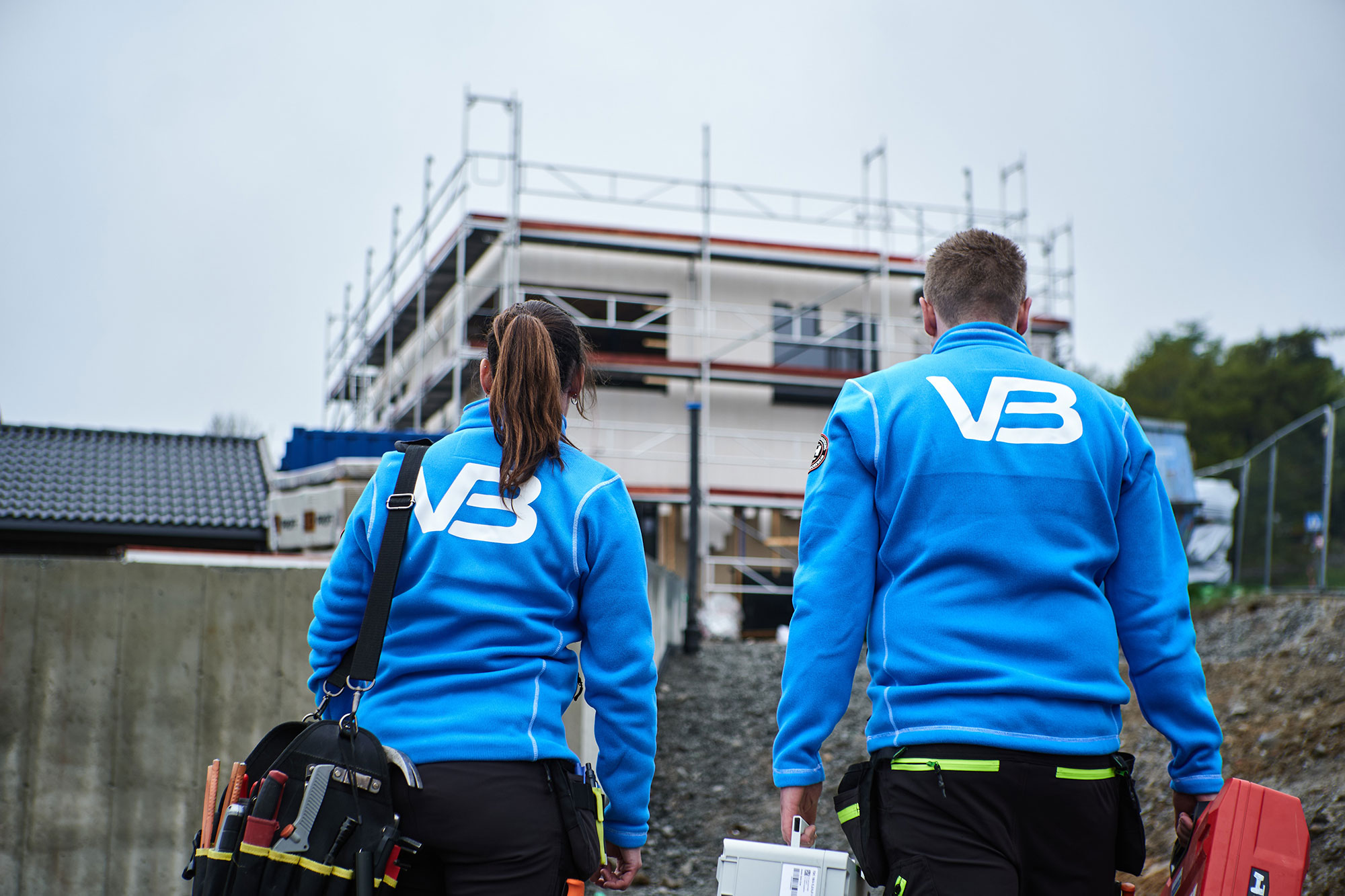 VB-rørleggere står foran et hus som renoveres med ryggen til